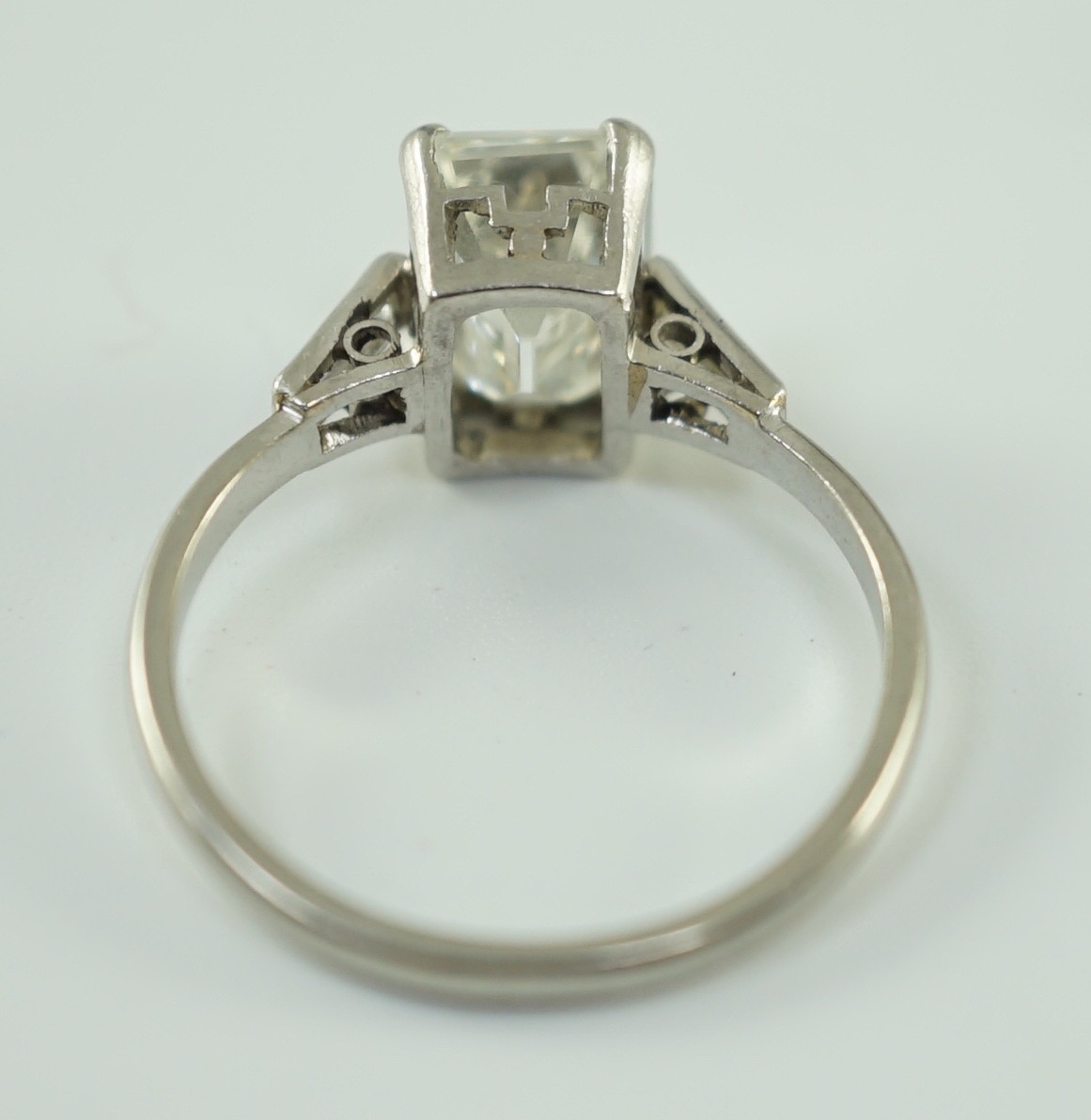 A platinum and single stone emerald cut diamond set ring, with baguette cut diamond set shoulders